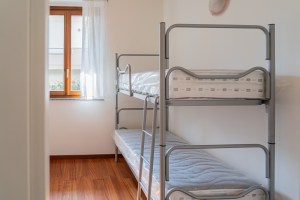 Immagine che mostra un letto a castello all'interno di una camera di uno degli appartamenti destinati all'housing sociale in Via delle Grigne