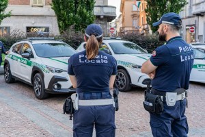 Immagine presa dalla pagina facebook della Città di Seregno, ritraente due agenti della Polizia Locale, di schiena, davanti a tre vetture in dotazione al Corpo, in Piazza Concordia, a Seregno.